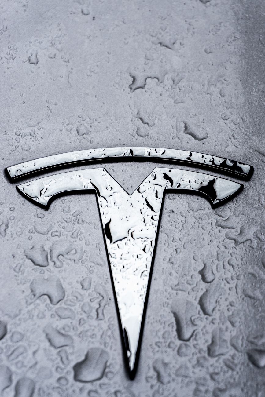 close up of tesla car emblem with raindrops